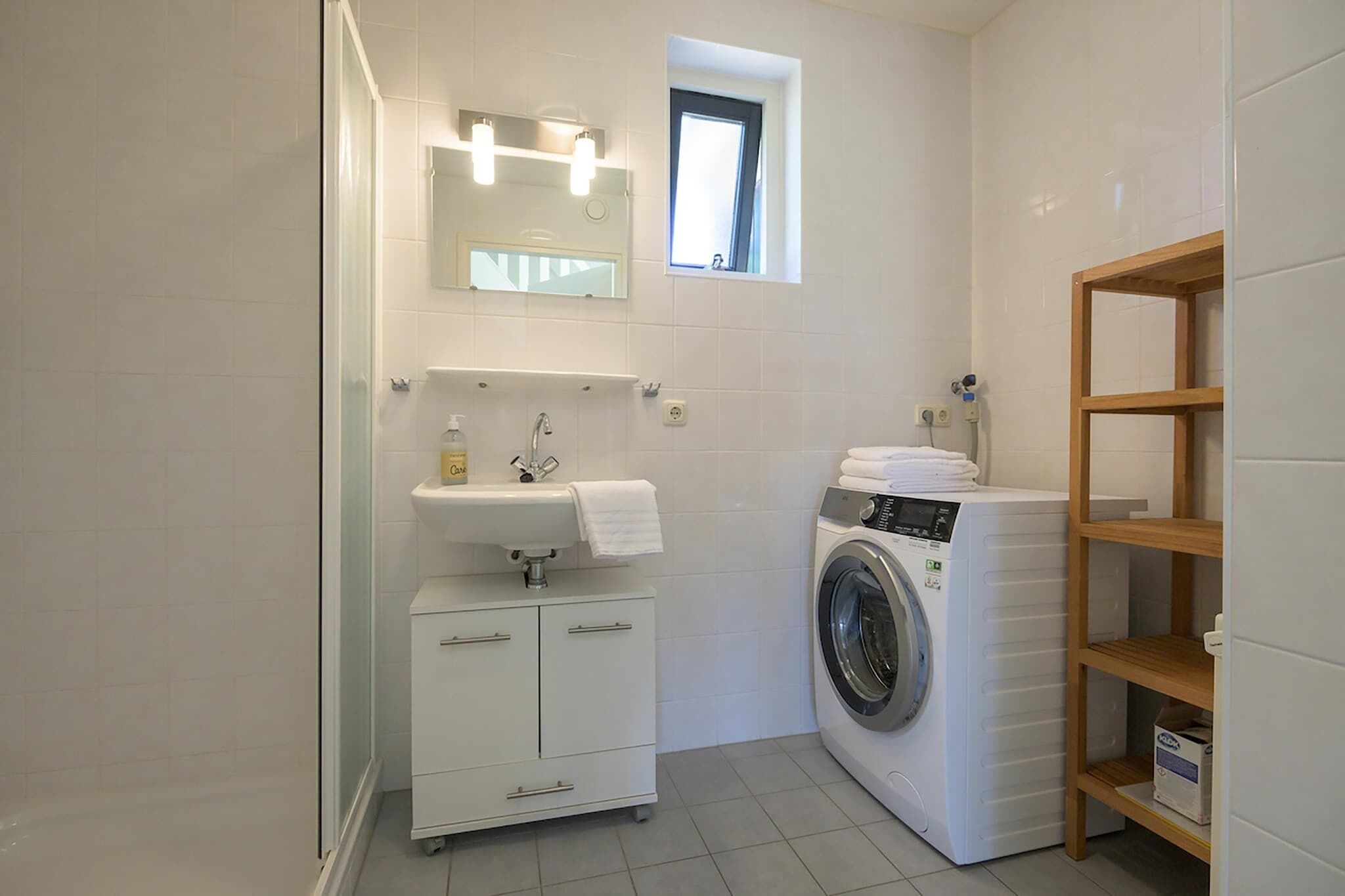 Un baño pequeño con lavamanos, espejo y lavadora.