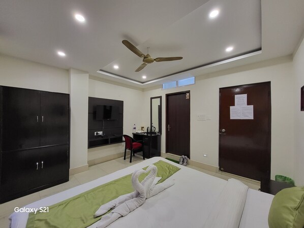 A hotel room with a bed, a desk, a wardrobe, a ceiling fan, and a TV. - The Star Continental & Spa (Gangtok)