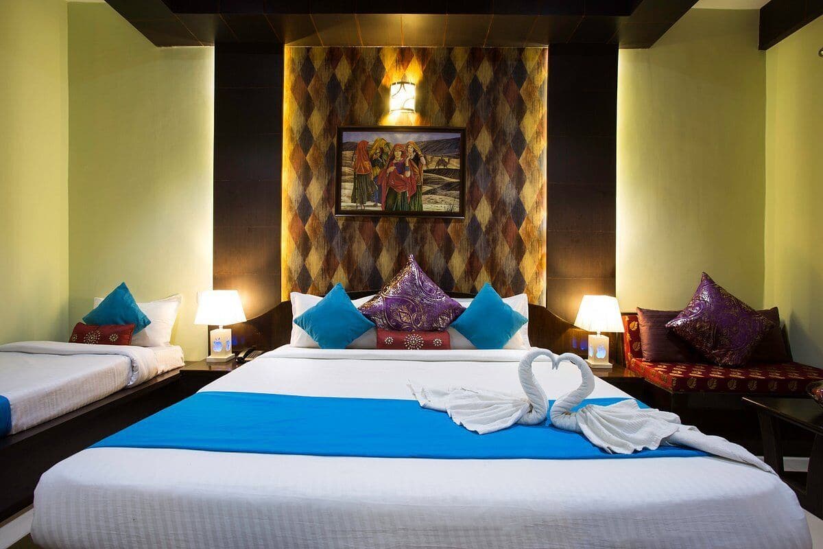 A hotel room with two beds, a large painting on the wall, and a decorative swan towel on the bed.