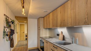 Una cocina moderna con armarios de madera, un lavamanos de acero inoxidable y una lámpara colgante.