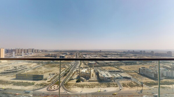 A high-rise building with a view of a cityscape, including roads, buildings, and a mosque. - The Community (Dubai)
