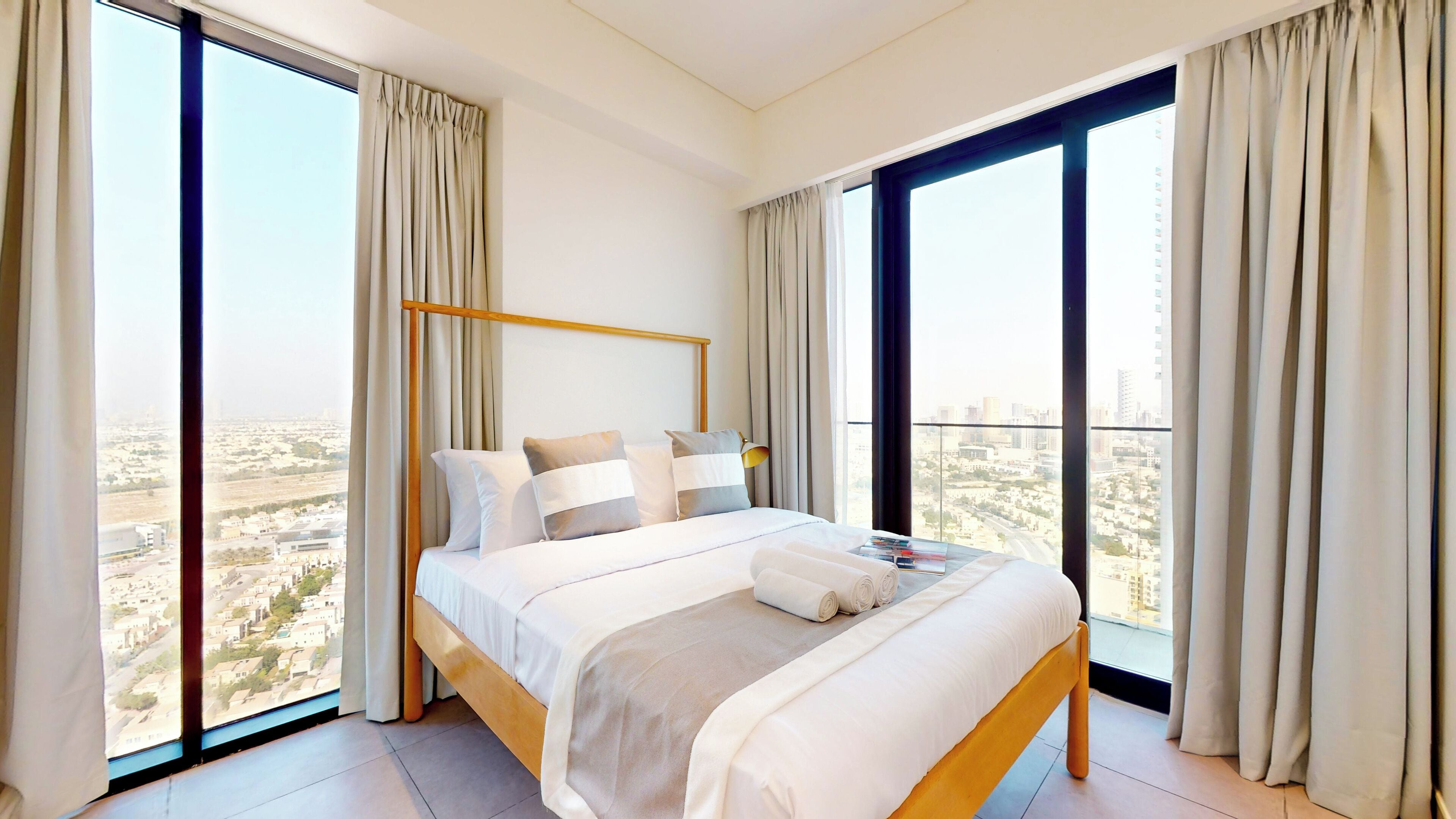 Une chambre d’hôtel moderne avec un grand lit, une vue sur la ville et de grandes fenêtres.