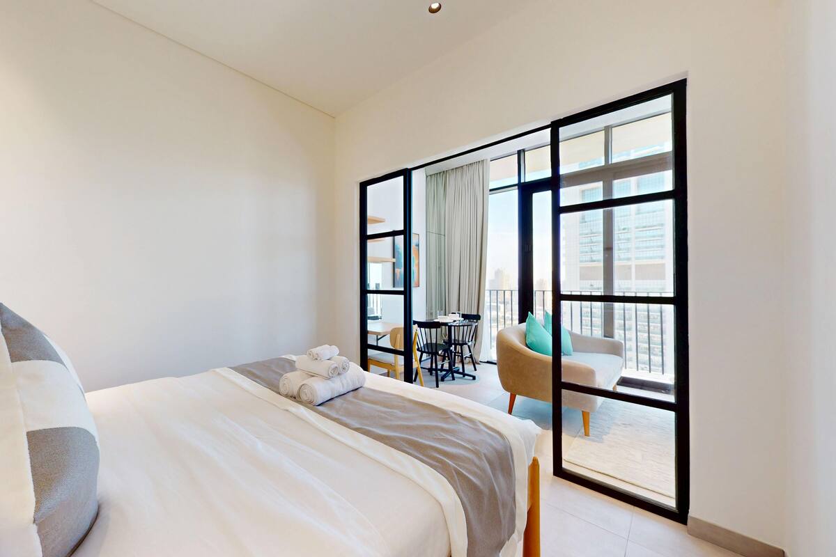 Une chambre d’hôtel moderne dotée d’un grand lit, d’un balcon avec vue et d’un coin repas.