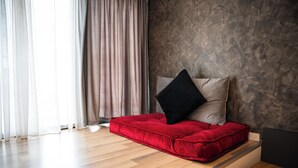 A modern room with a wooden floor, a red cushioned bench, a black pillow, and a textured wall. - Center Boutique Hotel (Tirana)
