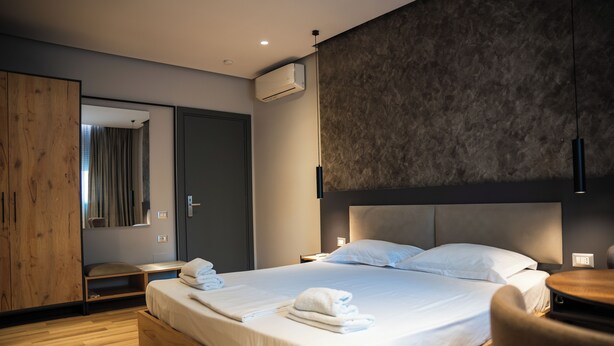 A modern hotel room with a large bed, wooden flooring, a wardrobe, and a mirror. - Center Boutique Hotel (Tirana)