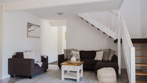 Ein Wohnzimmer mit zwei dunklen Sofas, einem weißen Couchtisch und einer Treppe mit weißen Geländern.