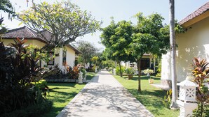 A pathway leading to a row of houses with a well-maintained lawn and various plants. - New Starlight Hotel & Resort (Buleleng)