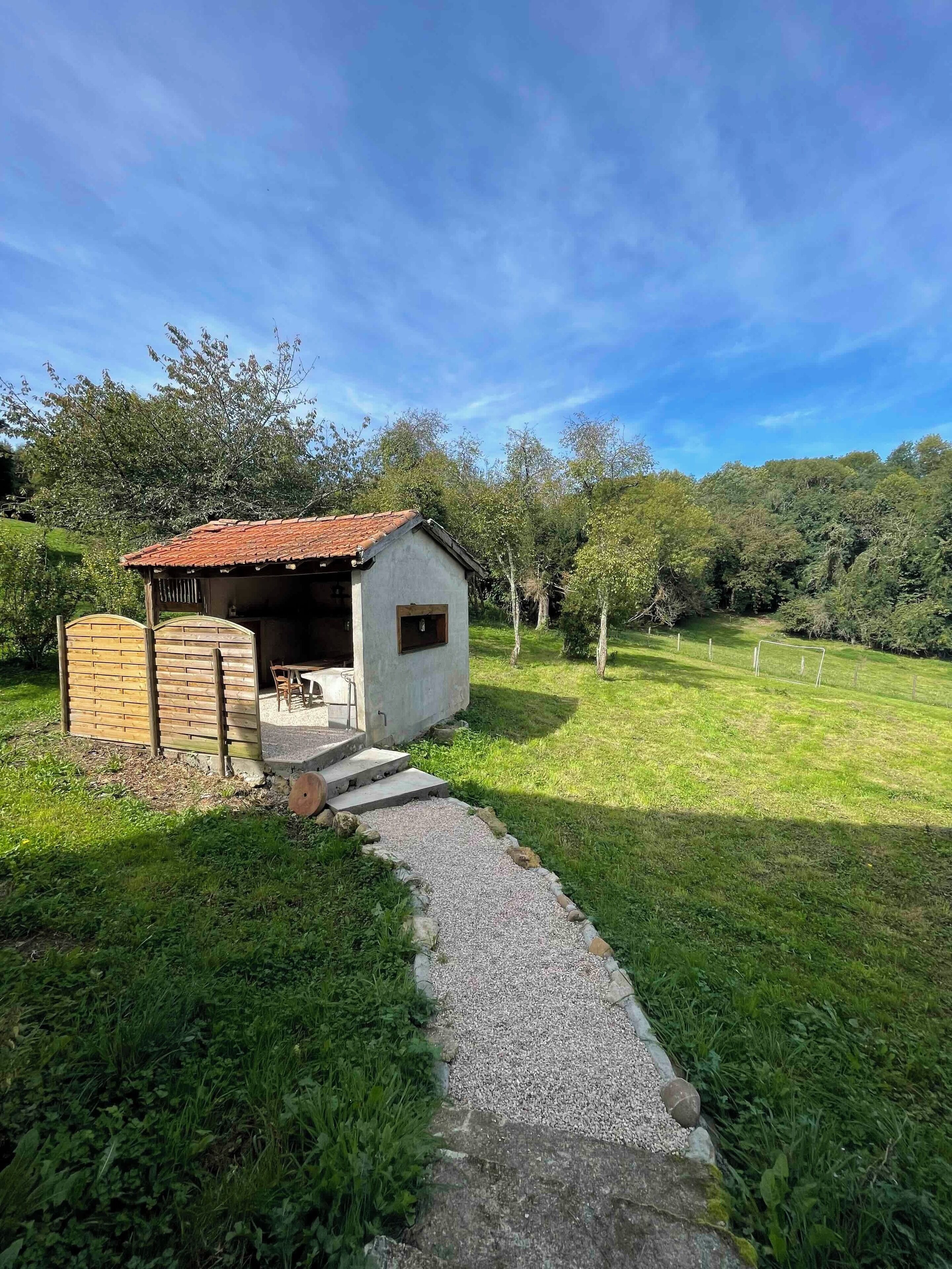 Un piccolo edificio rustico con tetto in tegole e un vialetto sterrato che vi conduce.
