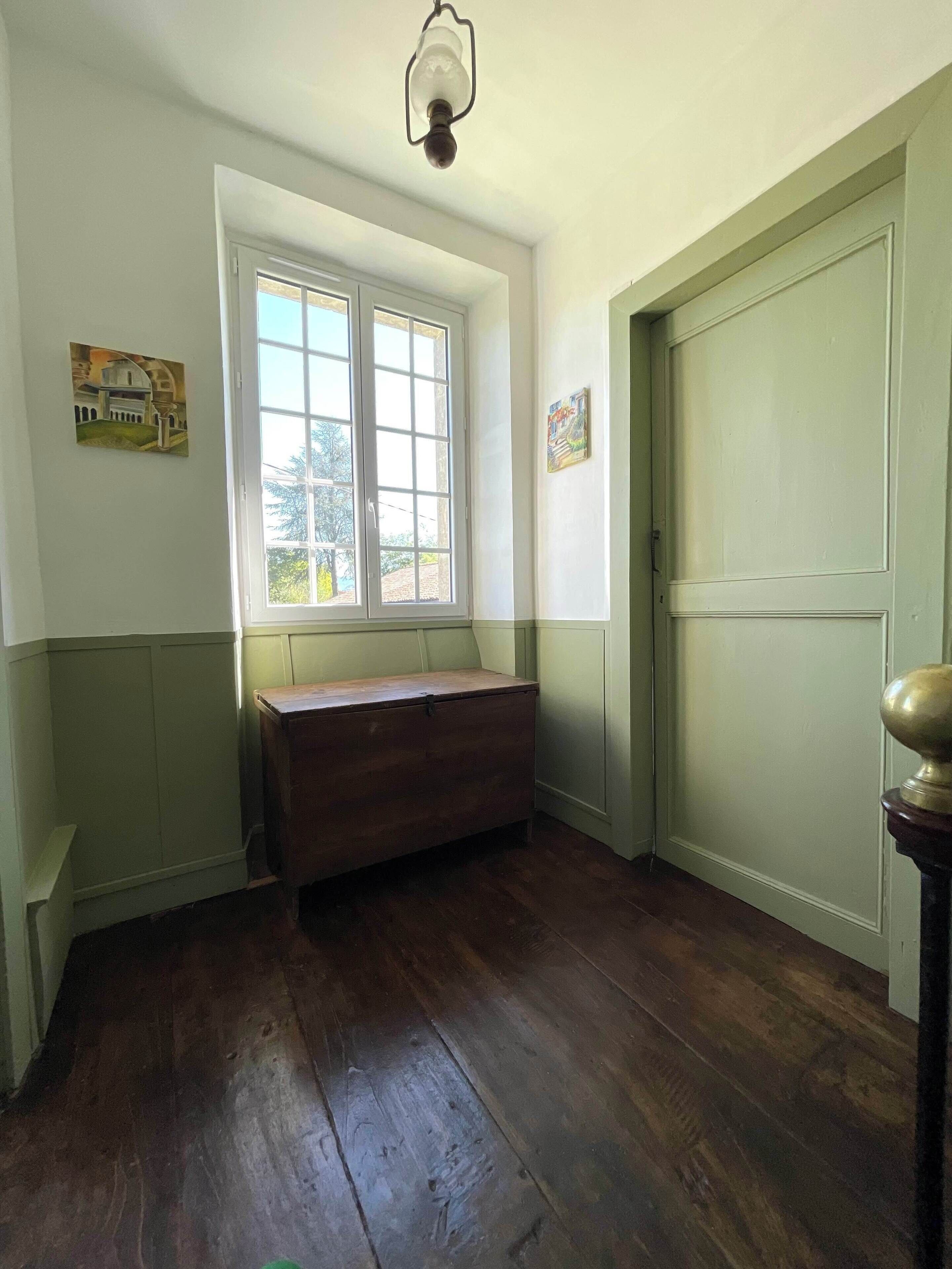 A room with a wooden bench, a window, a door, and a light fixture.