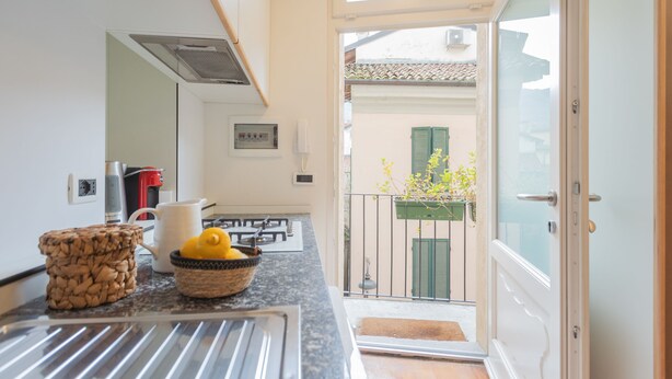 Una cocina con encimera de granito, cafetera, hervidor y una cesta de limones.