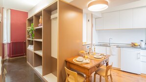 Una cocina moderna con armarios blancos, una mesa de comedor de madera y una estantería empotrada.