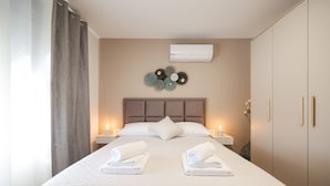 A neatly made bed with two towels, a wall-mounted air conditioner, and a decorative wall piece. - Villa Mindula (Sukosan)