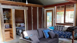 A cozy room with a grey sofa, a patterned rug, and a wooden ceiling. - Rainbow valley bunkhouse (Warrenbayne)
