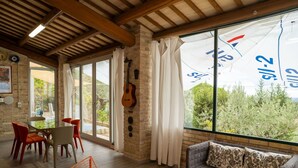 A spacious living room with a large window, a guitar wall, and a dining area with red chairs. - Wonderful  villa with WIFI, private pool, A/C, hot tub, patio, pets allowed and panoramic view (Città Sant'angelo)