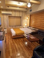 A hotel room with a bed, a sofa, a small table, and a TV.