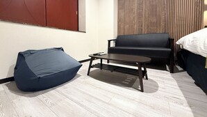 A modern room with a sofa, a small table, a bean bag, and a wooden panel wall.