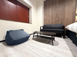 A modern room with a sofa, a small table, a bean bag, and a wooden panel wall.