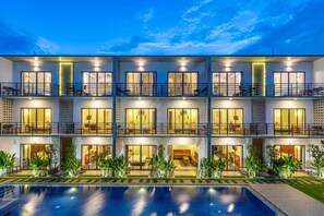 A multi-story hotel with balconies, a swimming pool, and well-lit rooms. - Phimean Home (Siem Reap)