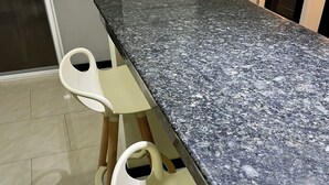 A kitchen with a granite countertop, two white bar stools, and a built-in oven.