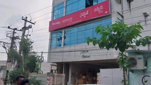 A multi-story building with a sign for 'Prestige Service' on the ground floor. - Smart Stay Rooms (Vijayawada)