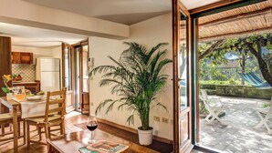 A dining area with a wooden table, chairs, a potted plant, and a glass of wine. - Villa Sorrentina With Panoramic Terrace (Massa Lubrense)