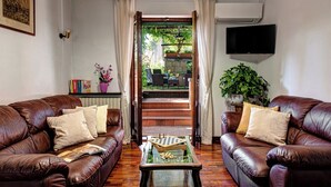 A living room with two leather sofas, a coffee table, and a bookshelf. There is a staircase leading to an outdoor area with a view of greenery. - Villa Sorrentina With Panoramic Terrace (Massa Lubrense)