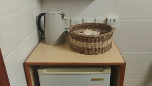 A small kitchenette with a coffee maker, a woven basket, and a small refrigerator. - HONG KONG SUN GUEST HOUSE (Kowloon)
