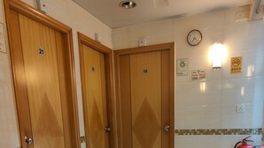 A hotel room with wooden doors numbered 19, 20, and 21, a white tiled floor, a red fire extinguisher, and a clock on the wall. - HONG KONG SUN GUEST HOUSE (Kowloon)