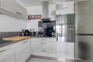 Una cocina moderna con electrodomésticos de acero inoxidable, una tabla de cortar de madera y vista al área de comedor.