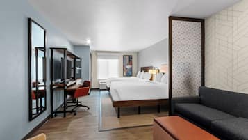 A hotel room with a bed, a desk with a chair, a sofa, and a bench.