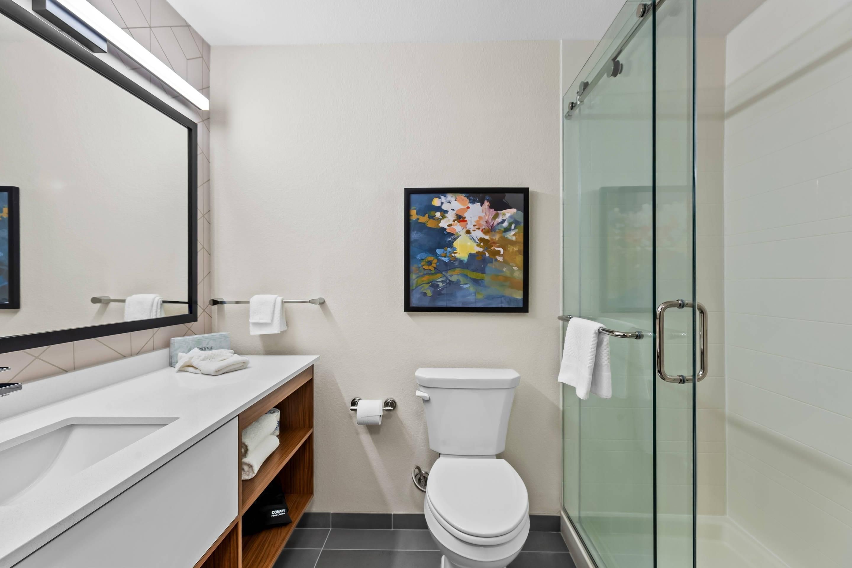 A modern bathroom with a white sink, toilet, and glass shower enclosure.