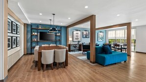 Una sala de estar moderna con una mesa de comedor de madera, un sofá azul y un televisor montado en la pared.