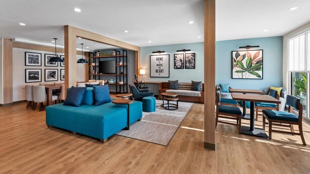 Una sala de estar moderna con un sofá azul, piso de madera y un comedor con mesa y sillas.