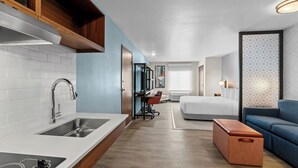 Una habitación de hotel moderna con kitchenette, una cama, un sofá y un pequeño rincón de descanso.