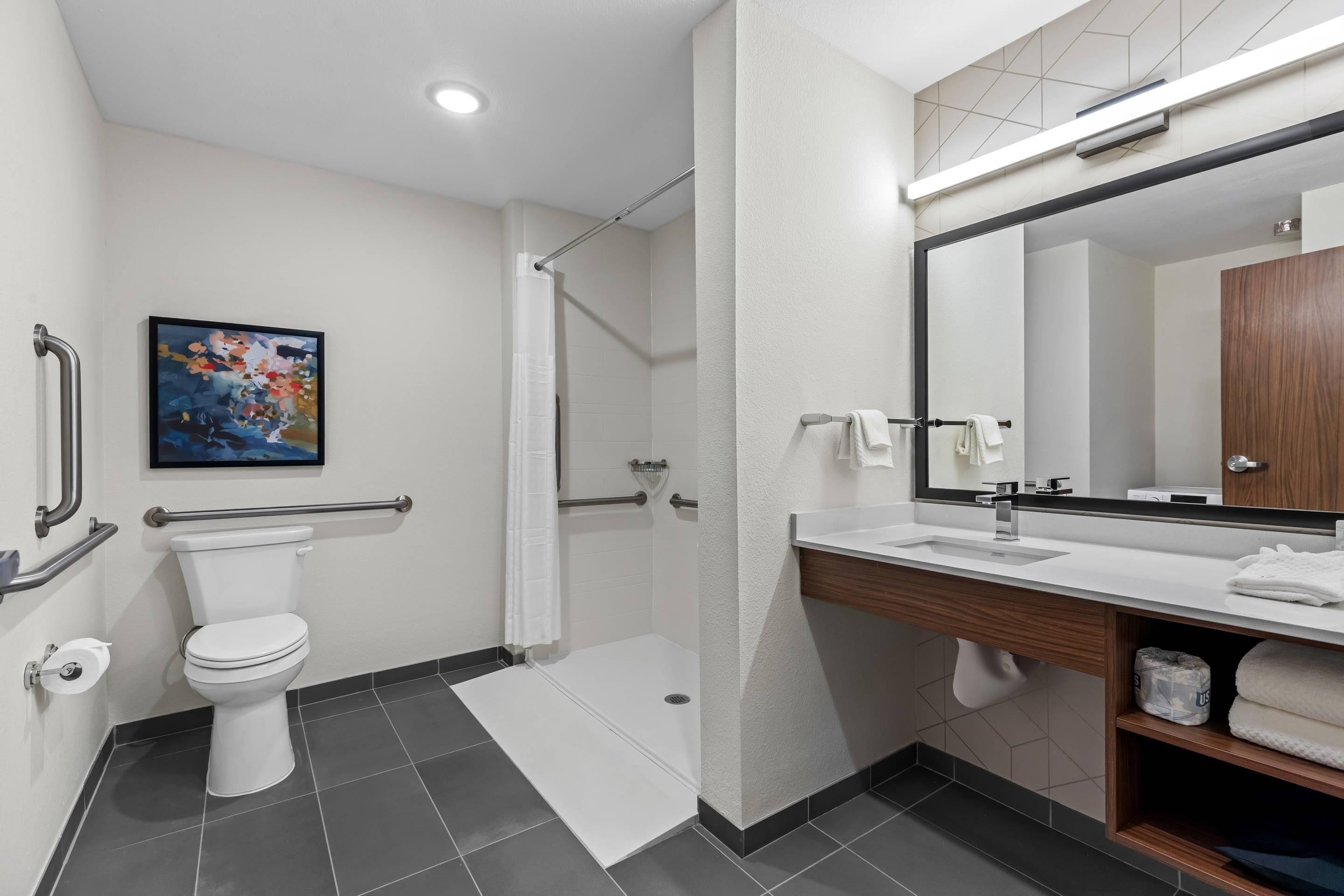 A modern bathroom with a toilet, shower, and sink.
