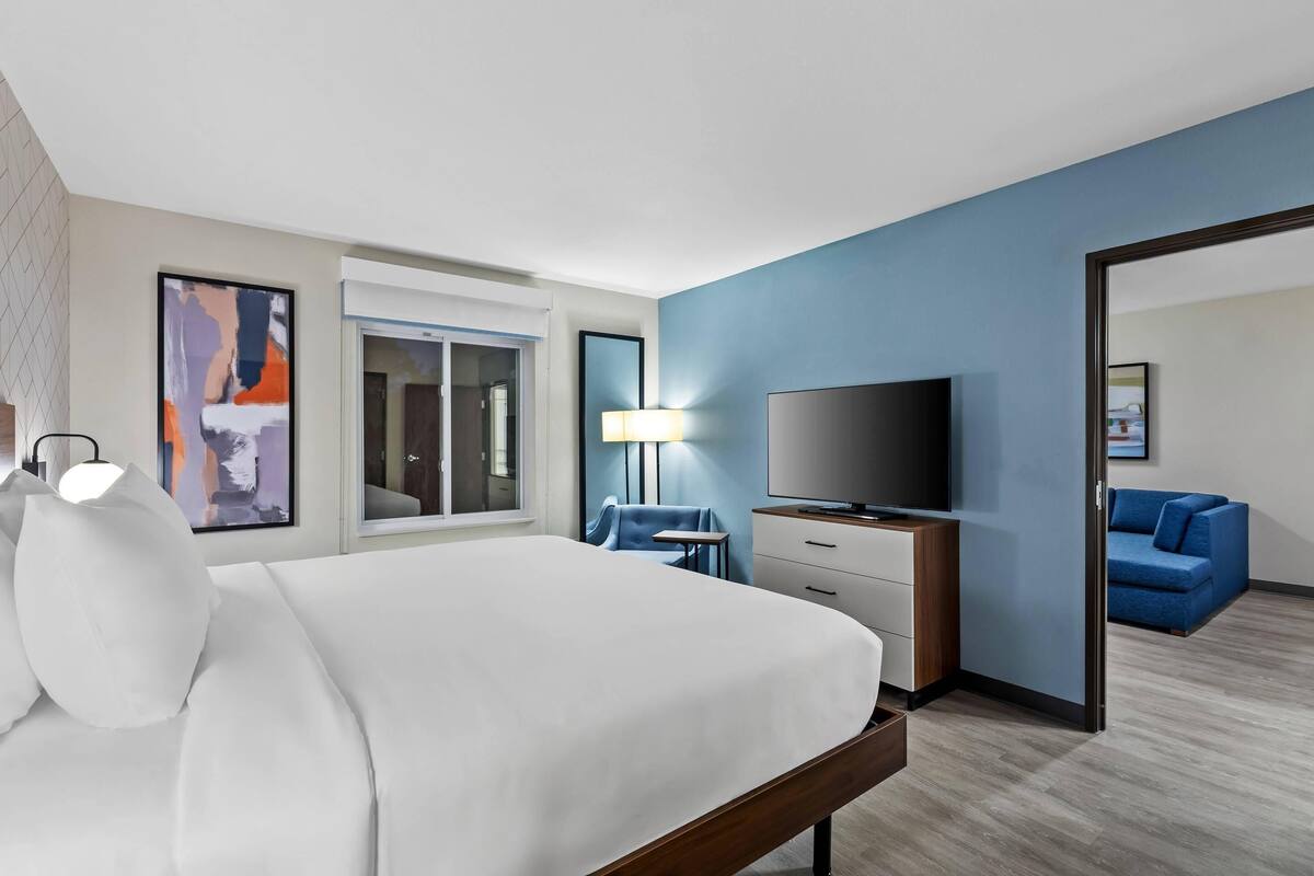 A hotel room with a large bed, a flat-screen TV, a desk, and a chair.