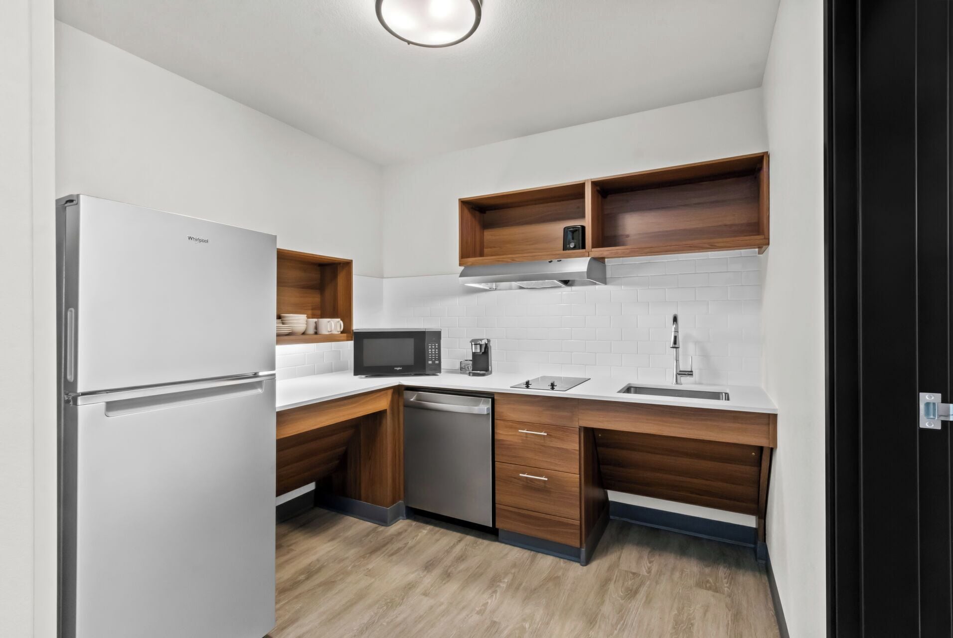 Eine kompakte Küche mit integriertem Kühlschrank, Mikrowelle und Geschirrspüler.
