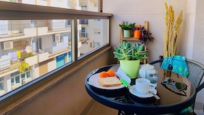 A balcony with a table set for tea, a plate of food, and a view of neighboring buildings. - Centric and Full of Light! Casa Alicia Altea (Altea)