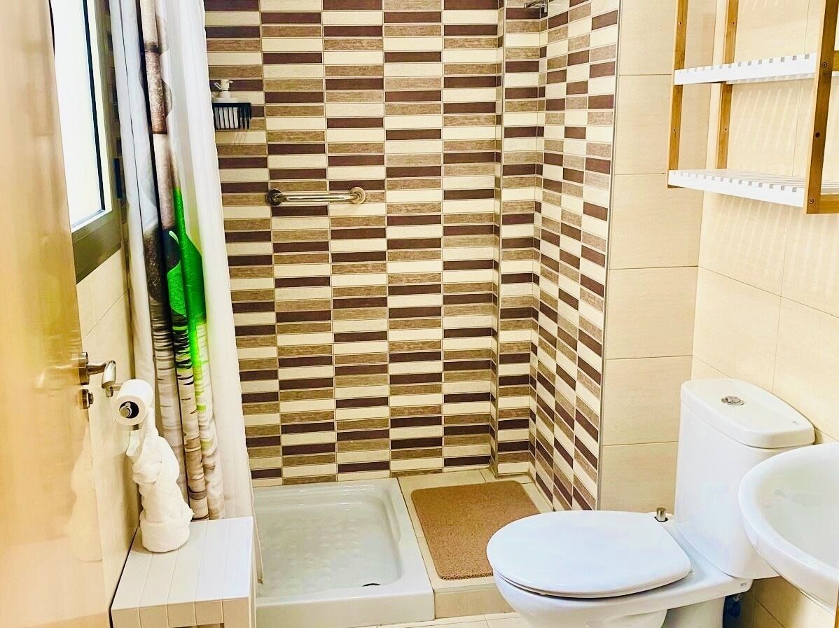A bathroom with a shower, toilet, and sink.