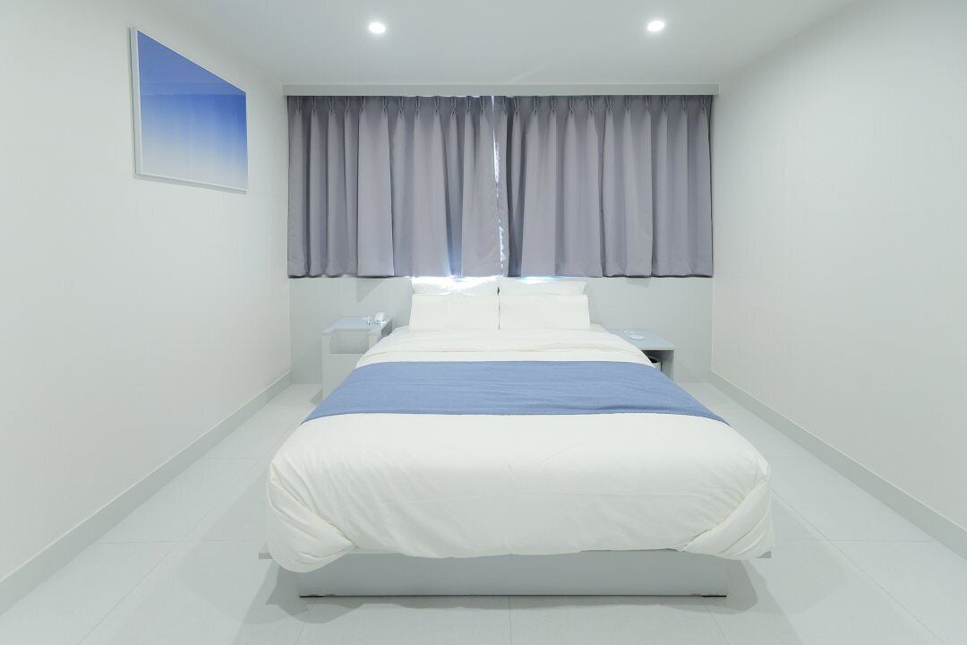 A modern bedroom with a bed, nightstands, and a window with curtains.