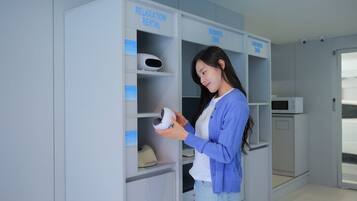 A person holding a VR headset in a room with labeled shelves for 'RELAXATION RENTAL' and 'BUSINESS ZONE'.