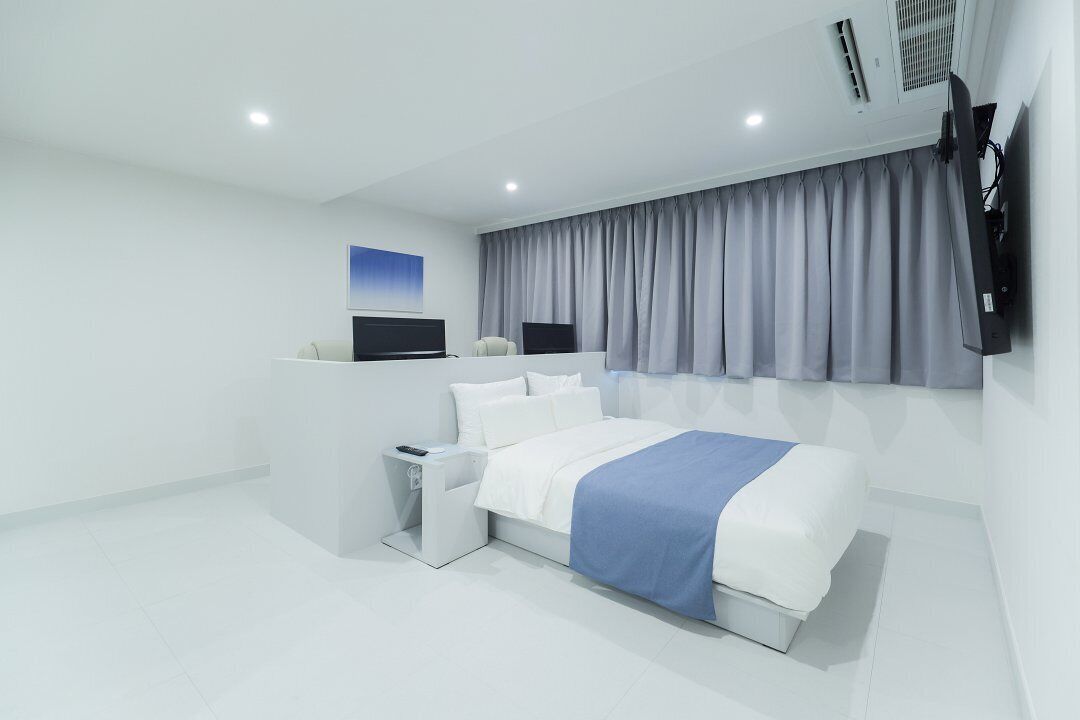 Una camera d'albergo moderna con un letto grande, una TV a schermo piatto, una scrivania e una finestra con tende.