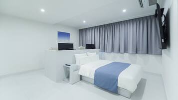 Una camera d'albergo moderna con un letto grande, una TV a schermo piatto, una scrivania e una finestra con tende.