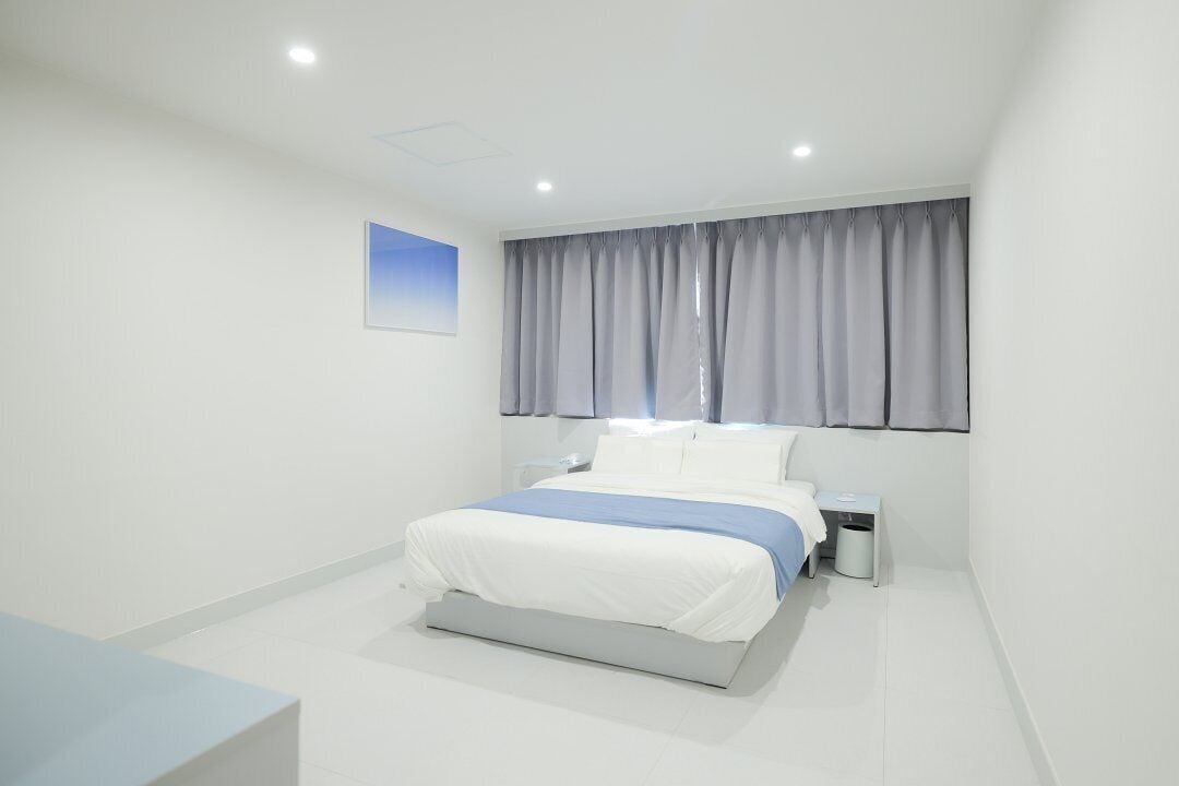 A modern bedroom with a bed, bedside table, and a window with curtains.