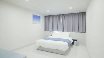 A modern bedroom with a bed, bedside table, and a window with curtains.
