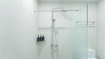Un baño moderno con azulejos blancos, cabina de ducha de vidrio y un inodoro.