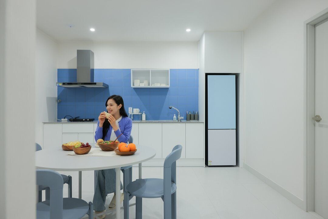 A modern kitchen with a dining table, chairs, and a person eating.