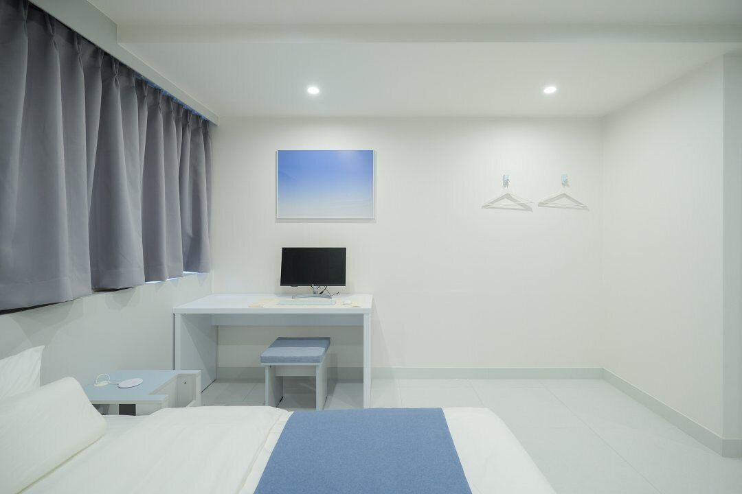 Ein Hotelzimmer mit einem Bett, einem Schreibtisch mit Computer, einem kleinen Tisch und einem Sessel.
