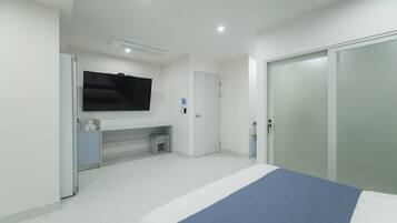 A modern bedroom with a bed, a desk, a TV, and a wardrobe.