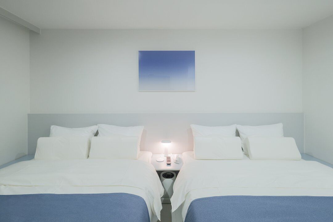 Habitación de hotel con una cama, dos mesitas de noche y una lámpara fijada a la pared.